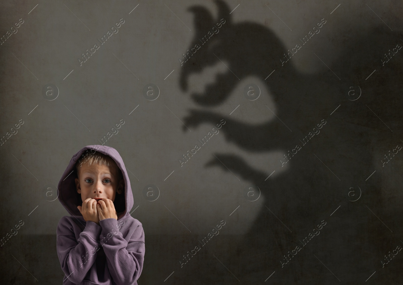 Image of Little kid scared by monster. Spooky shadow in wall