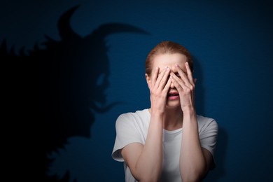 Woman scared by monster. Creepy shadow on blue wall