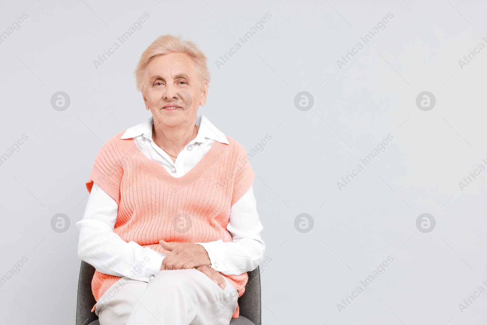 Photo of Senior woman on chair against light background. Space for text