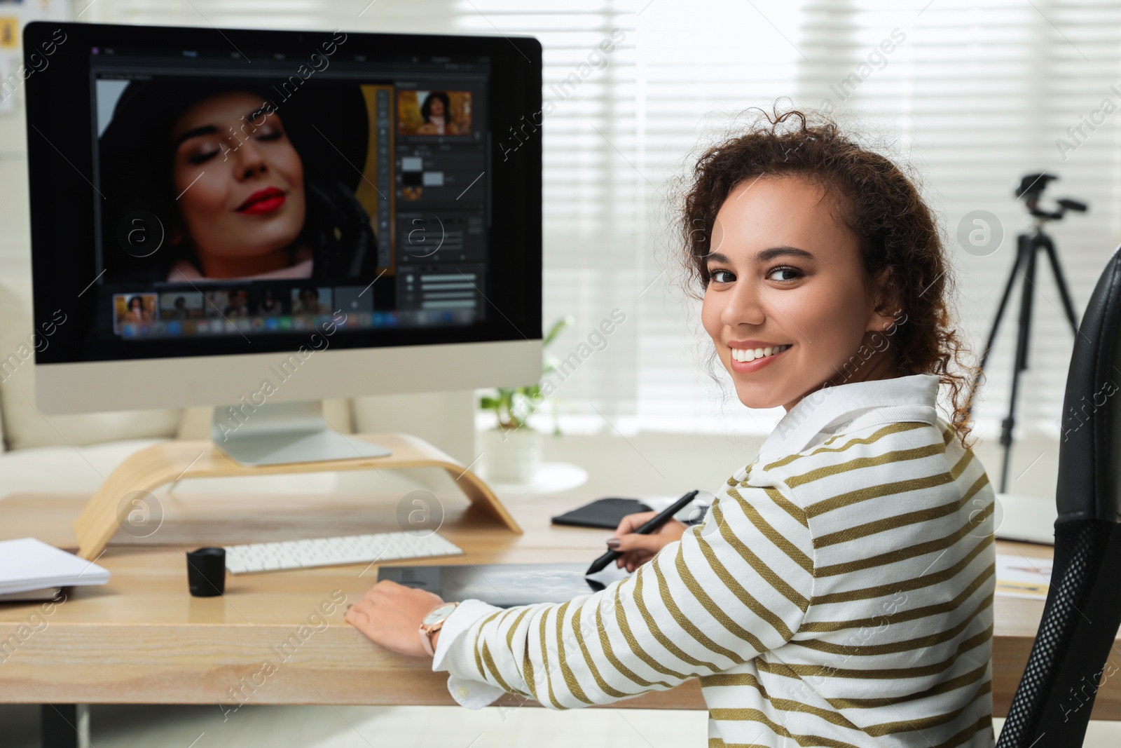 Photo of Professional African American retoucher working with graphic tablet at desk in office