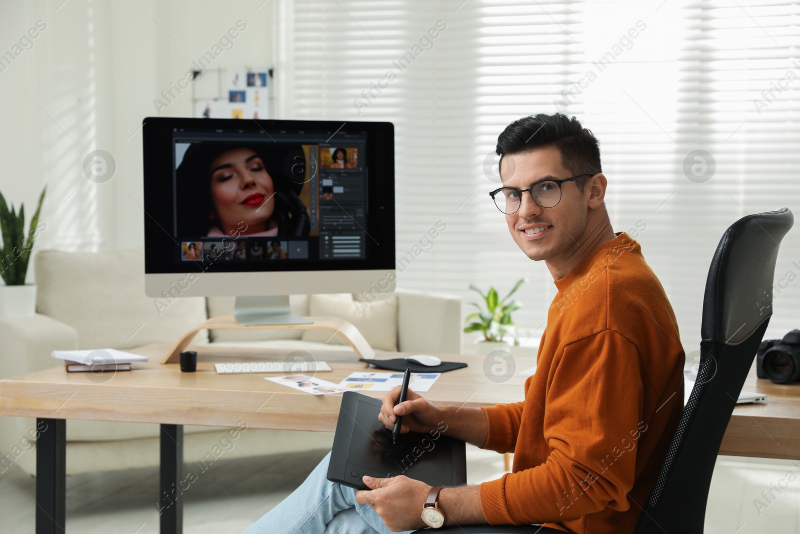 Photo of Professional retoucher working with graphic tablet at desk in office