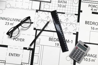 Ruler, glasses, calculator and pencil on different architectural drawings, top view