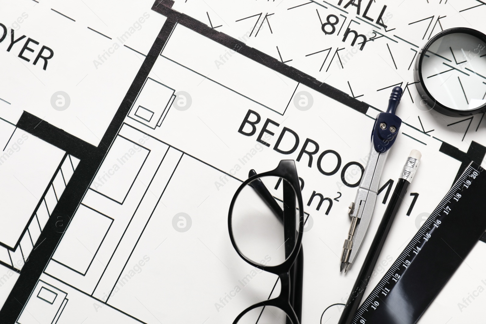 Photo of Ruler, glasses, dividers, magnifying glass and pencil on different architectural drawings, top view