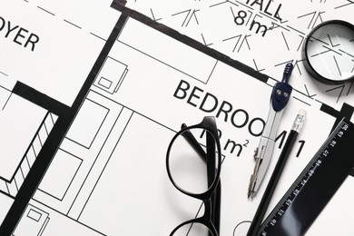 Photo of Ruler, glasses, dividers, magnifying glass and pencil on different architectural drawings, top view