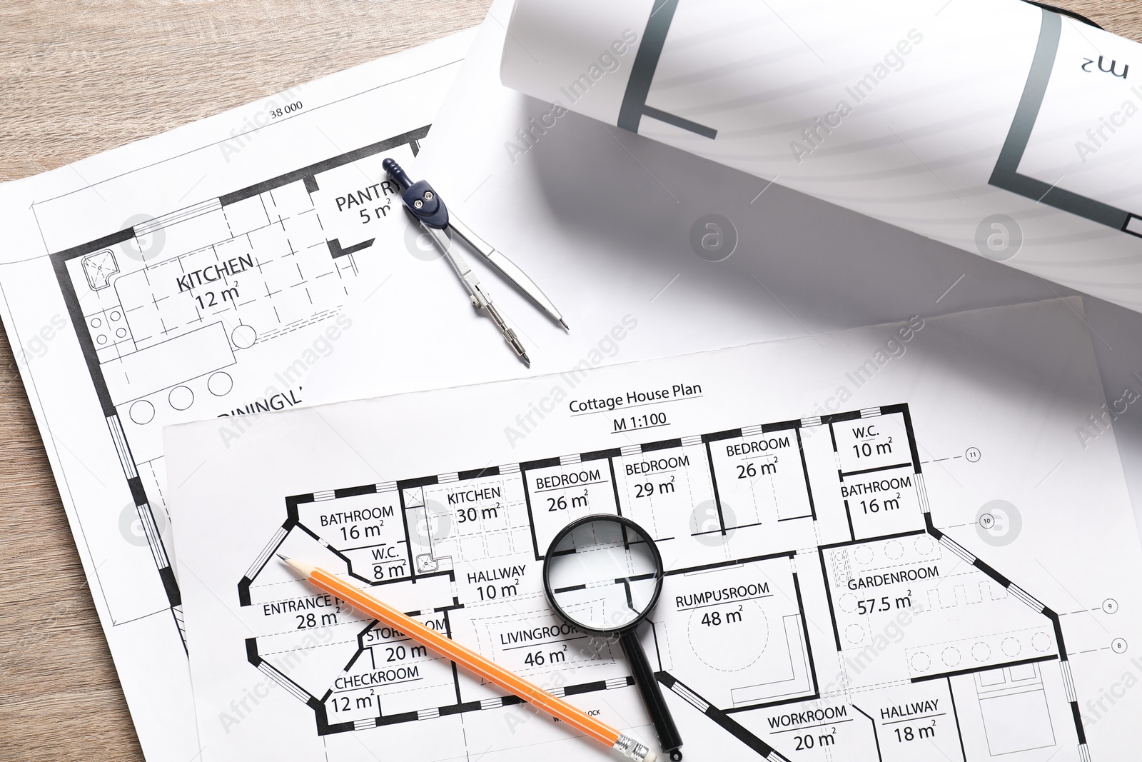 Photo of Different architectural drawings, dividers, pencil and magnifying glass on wooden table, top view