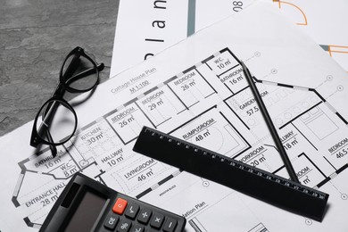 Different architectural drawings, glasses, calculator and ruler on grey textured table, flat lay