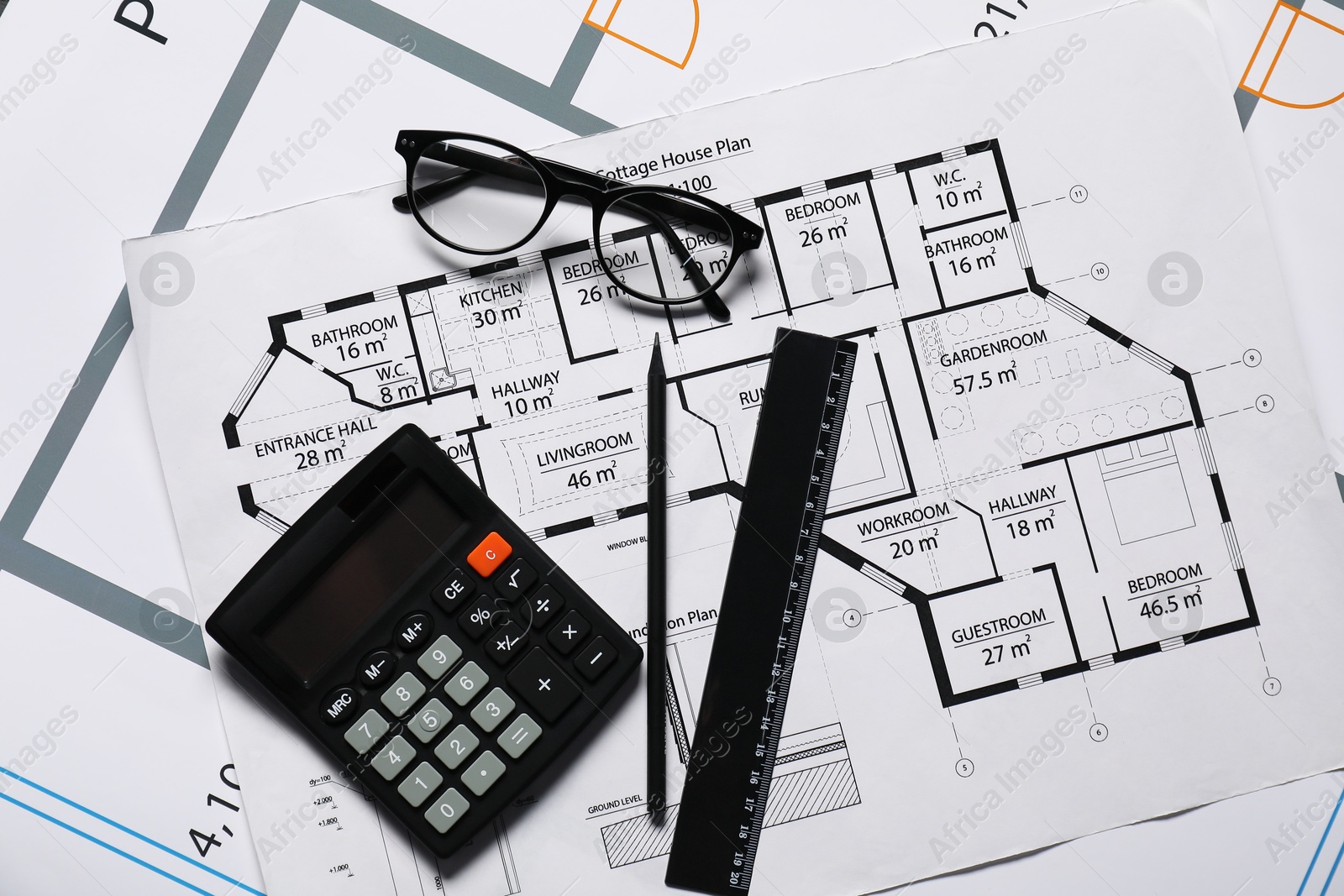 Photo of Glasses, calculator and ruler on different architectural drawings, flat lay