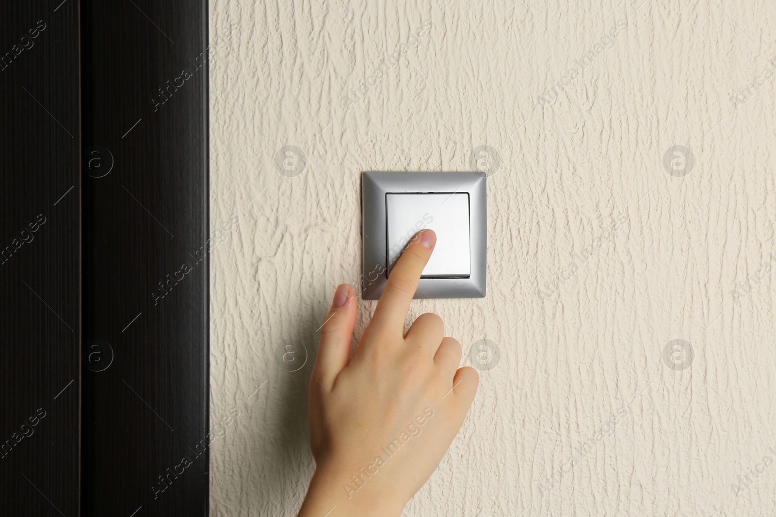 Photo of Woman turning light switch on, closeup view