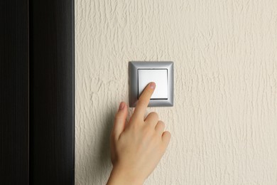 Photo of Woman turning light switch on, closeup view