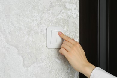 Photo of Woman turning light switch on, closeup view