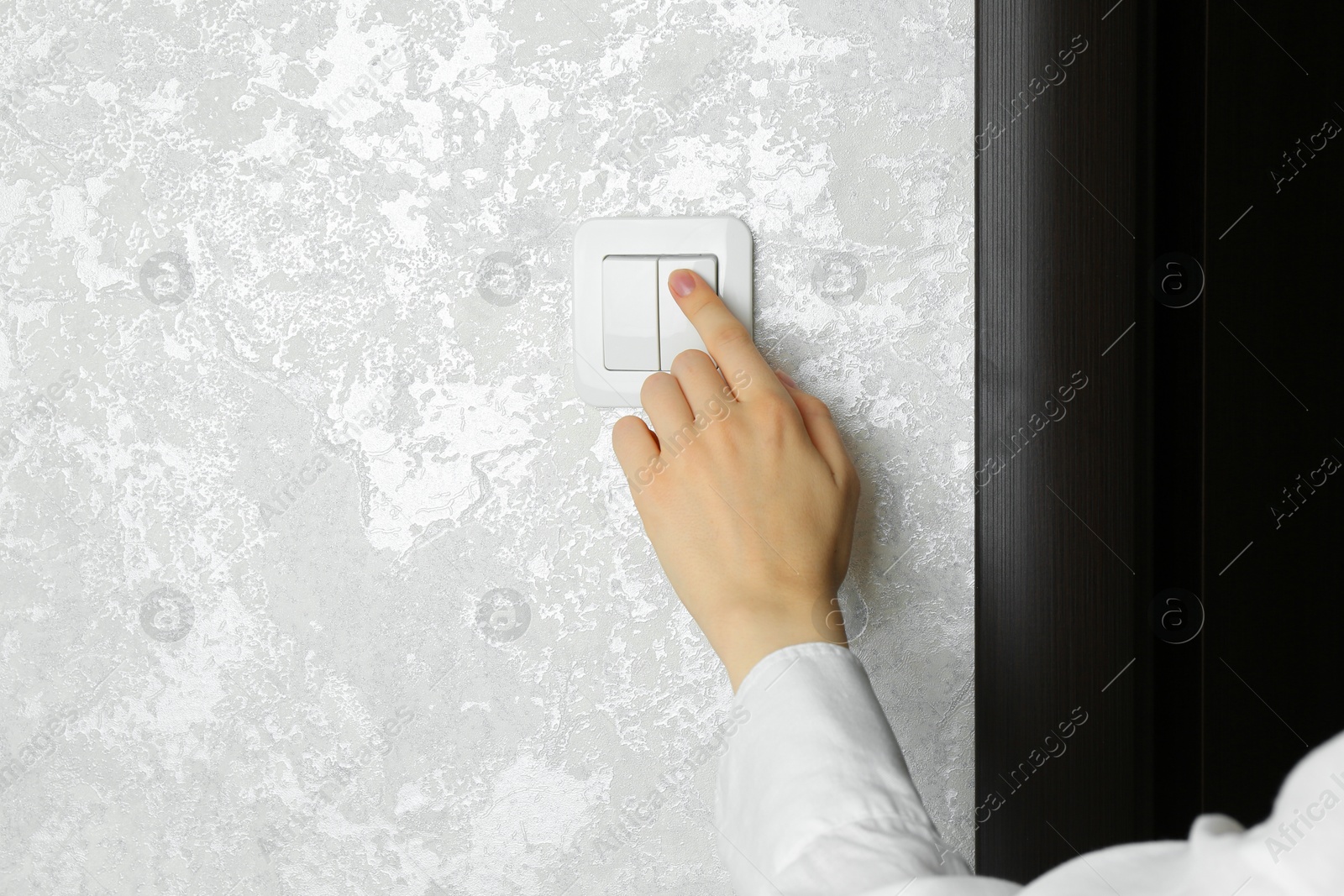 Photo of Woman turning light switch on, closeup view