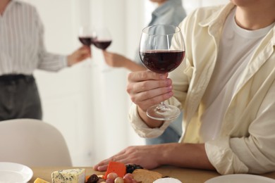 People with glasses of red wine indoors, selective focus