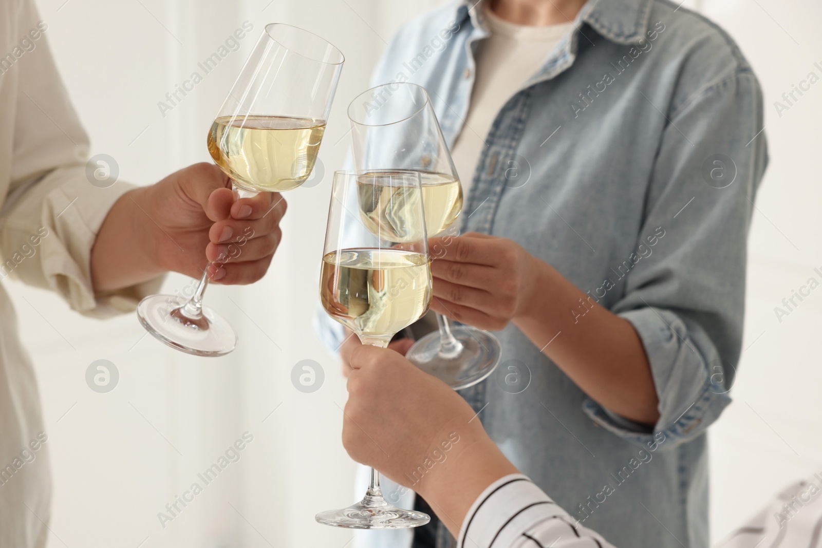 Photo of People clinking glasses of wine indoors, closeup