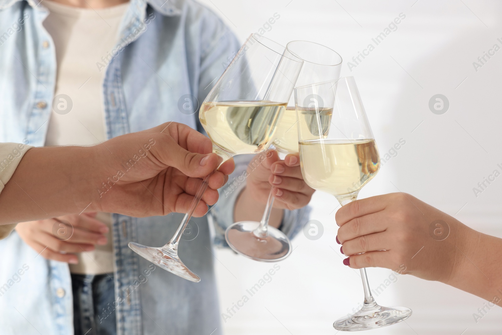 Photo of People clinking glasses of wine indoors, closeup