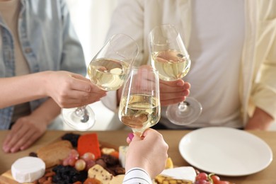 Photo of People clinking glasses of wine at served table, closeup