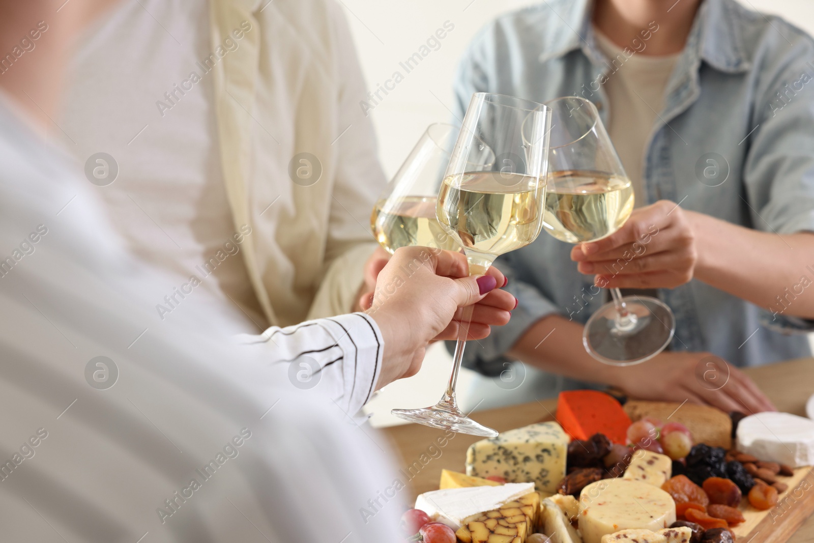 Photo of People clinking glasses of wine at served table, closeup