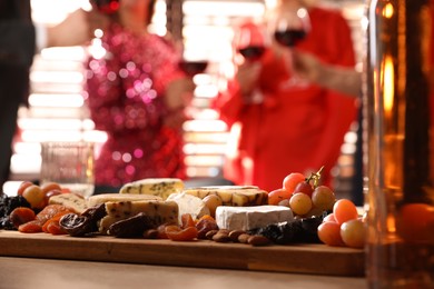 Photo of People clinking glasses of wine at party, focus on table with snacks