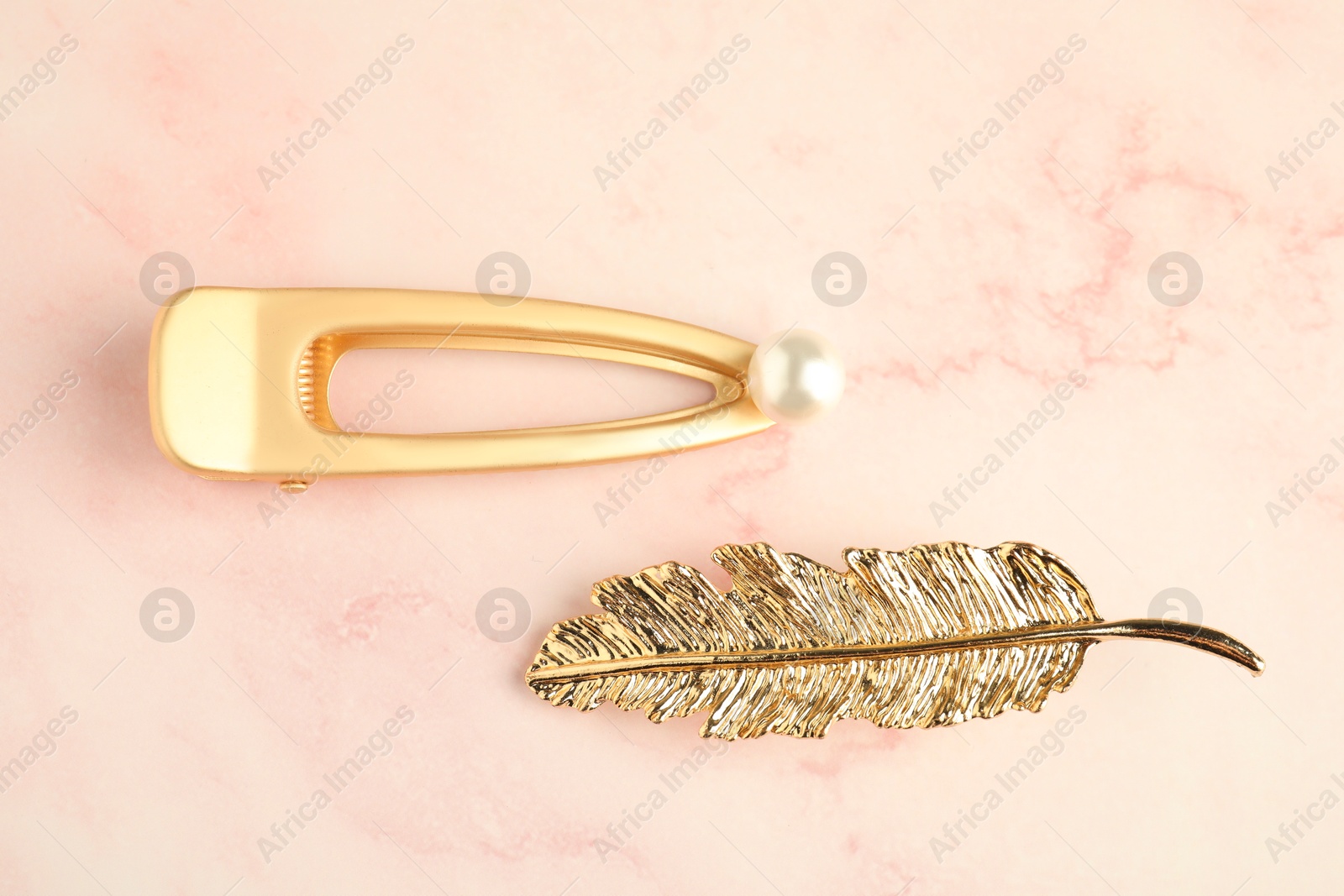 Photo of Beautiful bijouterie. Elegant hair clips on light pink background, top view