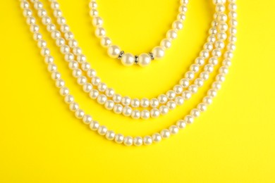 Photo of Beautiful bijouterie. Stylish necklace and bracelet on yellow background, top view