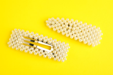 Photo of Beautiful bijouterie. Elegant hair clips on yellow background, top view