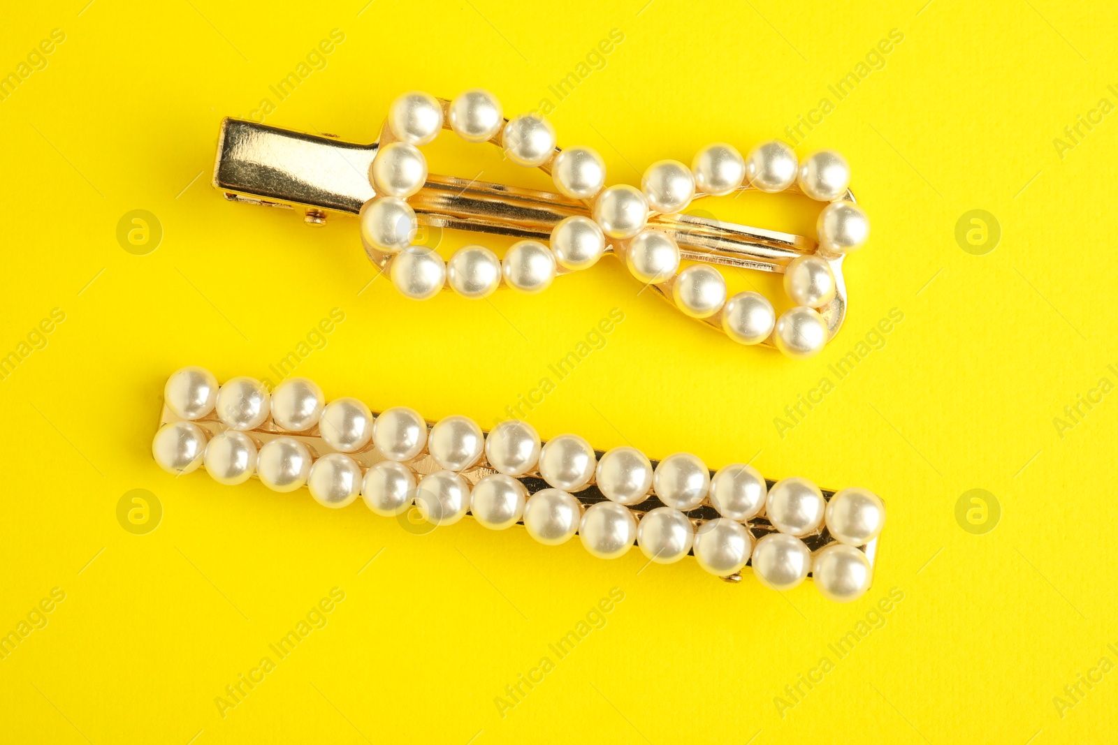 Photo of Beautiful bijouterie. Elegant hair clips on yellow background, top view