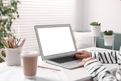 Photo of Woman working with laptop at table in office, closeup. Mockup for design