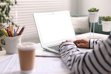 Photo of Woman working with laptop at table in office, closeup. Mockup for design