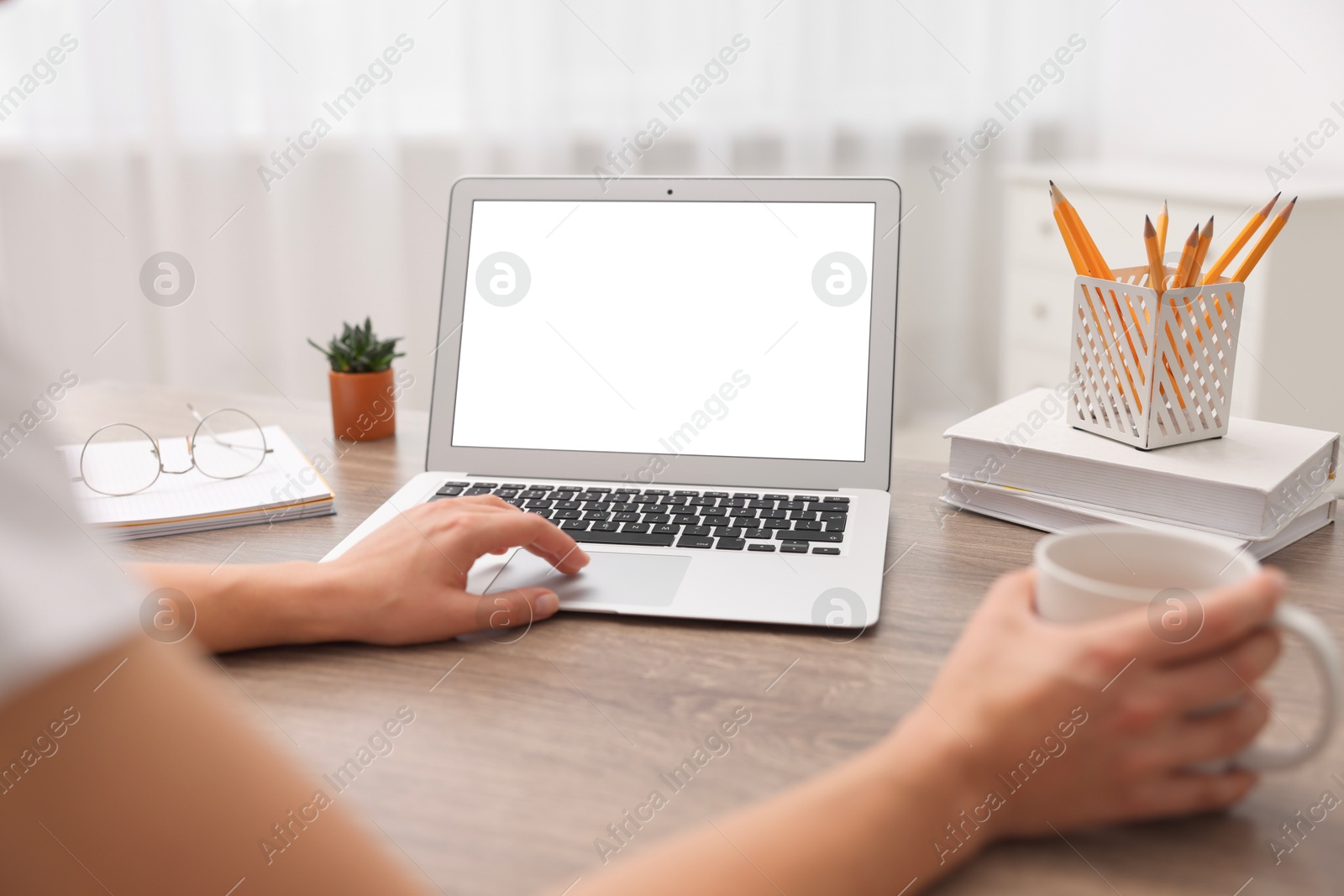 Photo of Woman working with laptop at wooden table in office, closeup. Mockup for design