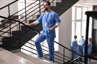 Photo of Healthcare workers in hospital, selective focus. Smiling nurse walking up stairs indoors