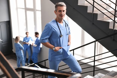 Smiling healthcare worker with stethoscope walking up stairs in hospital