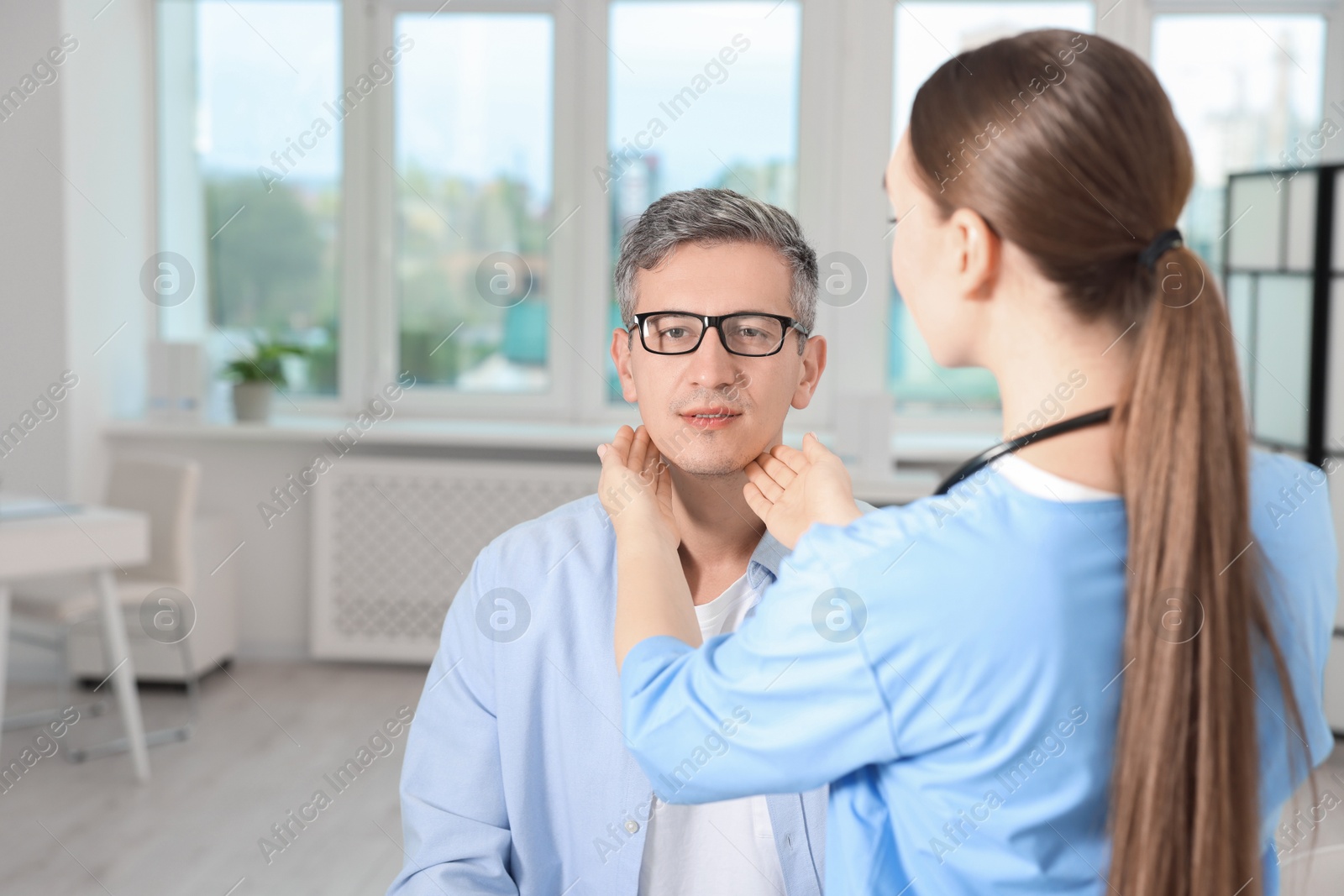 Photo of Doctor examining man's throat in clinic during appointment