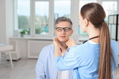 Photo of Doctor examining man's throat in clinic during appointment