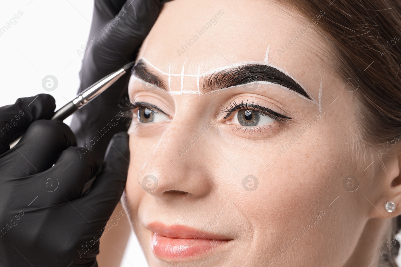 Photo of Young woman undergoing henna eyebrows dyeing procedure on light background, closeup