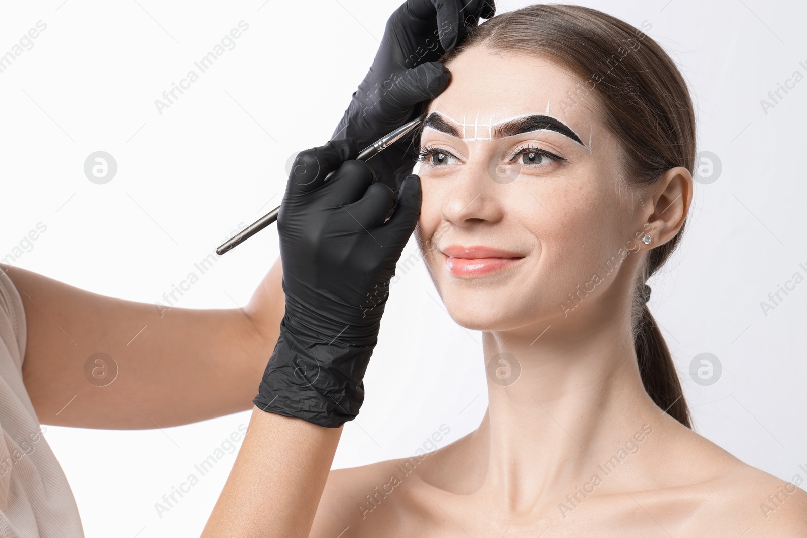 Photo of Young woman undergoing henna eyebrows dyeing procedure on white background, closeup