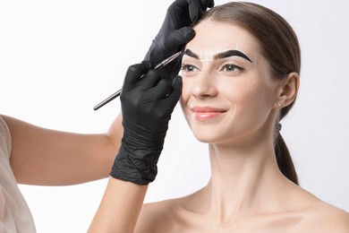 Photo of Young woman undergoing henna eyebrows dyeing procedure on white background, closeup