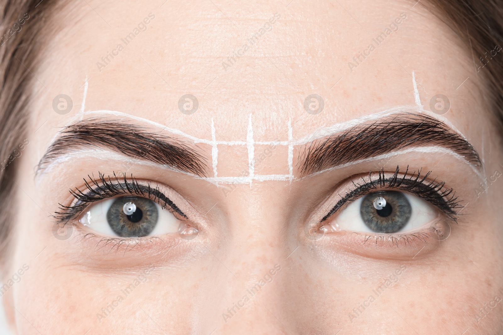 Photo of Young woman during henna eyebrows dyeing procedure, closeup