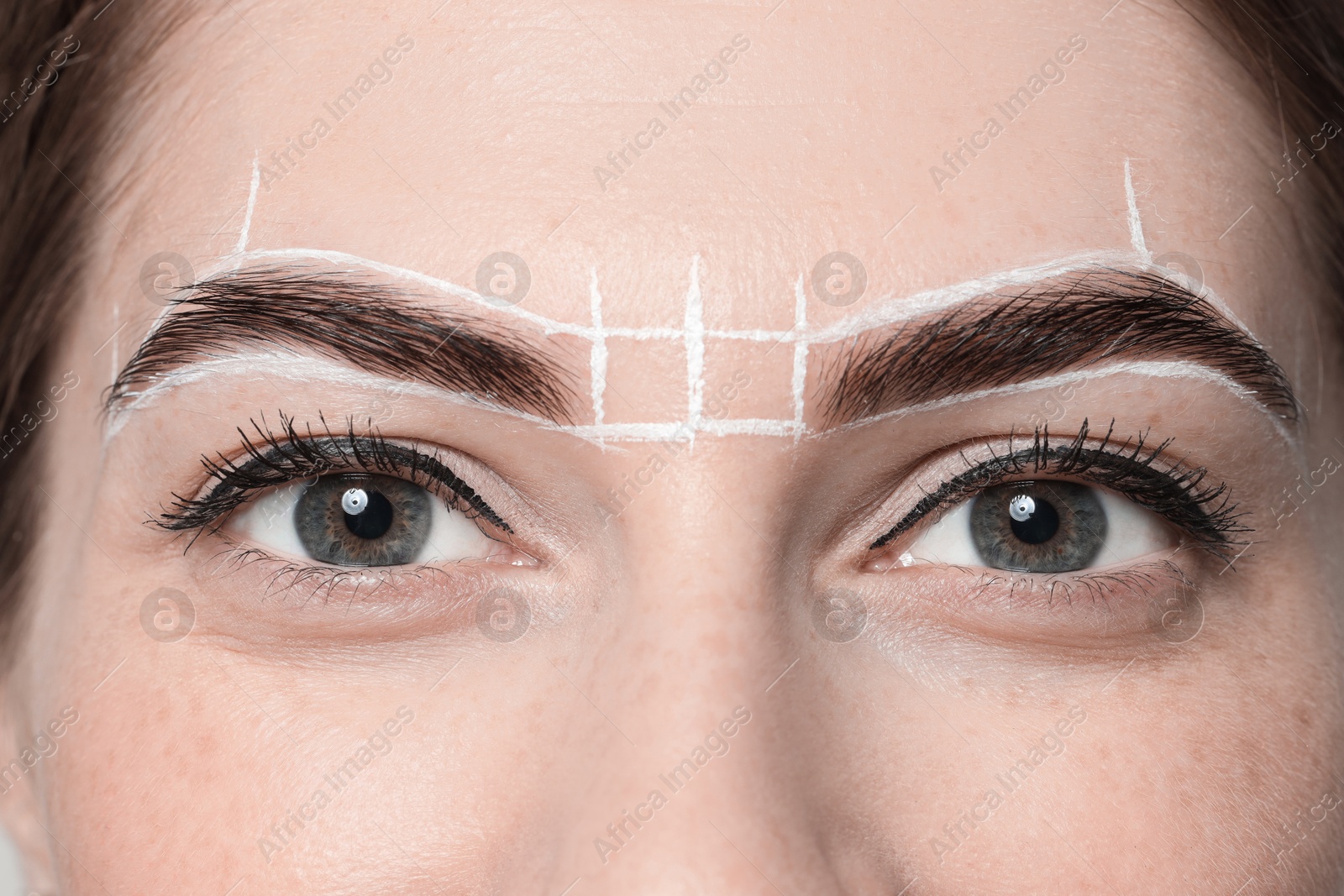 Photo of Young woman during henna eyebrows dyeing procedure, closeup