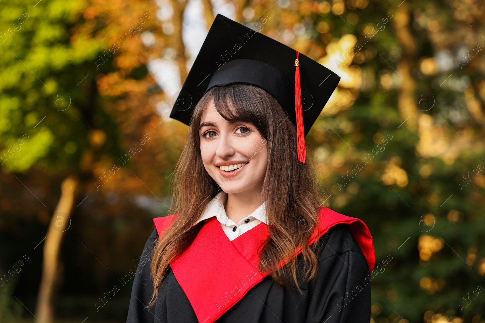 Photo of Graduation ceremony. Happy student in academic dress outdoors