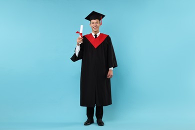 Photo of Happy student with diploma after graduation on light blue background