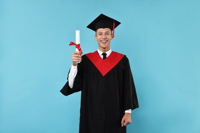 Photo of Happy student with diploma after graduation on light blue background