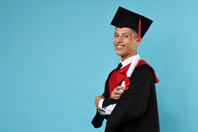 Photo of Happy student with diploma after graduation on light blue background. Space for text