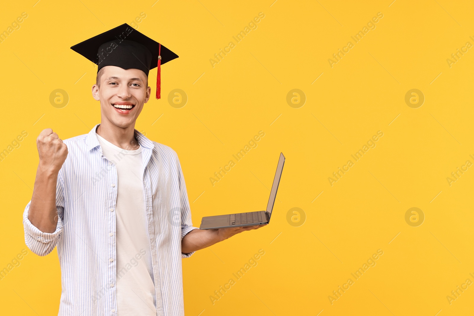 Photo of Happy student with laptop after graduation on orange background. Space for text