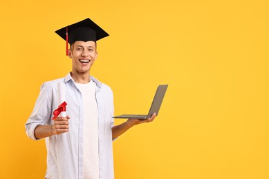 Photo of Happy student with diploma and laptop after graduation on orange background. Space for text