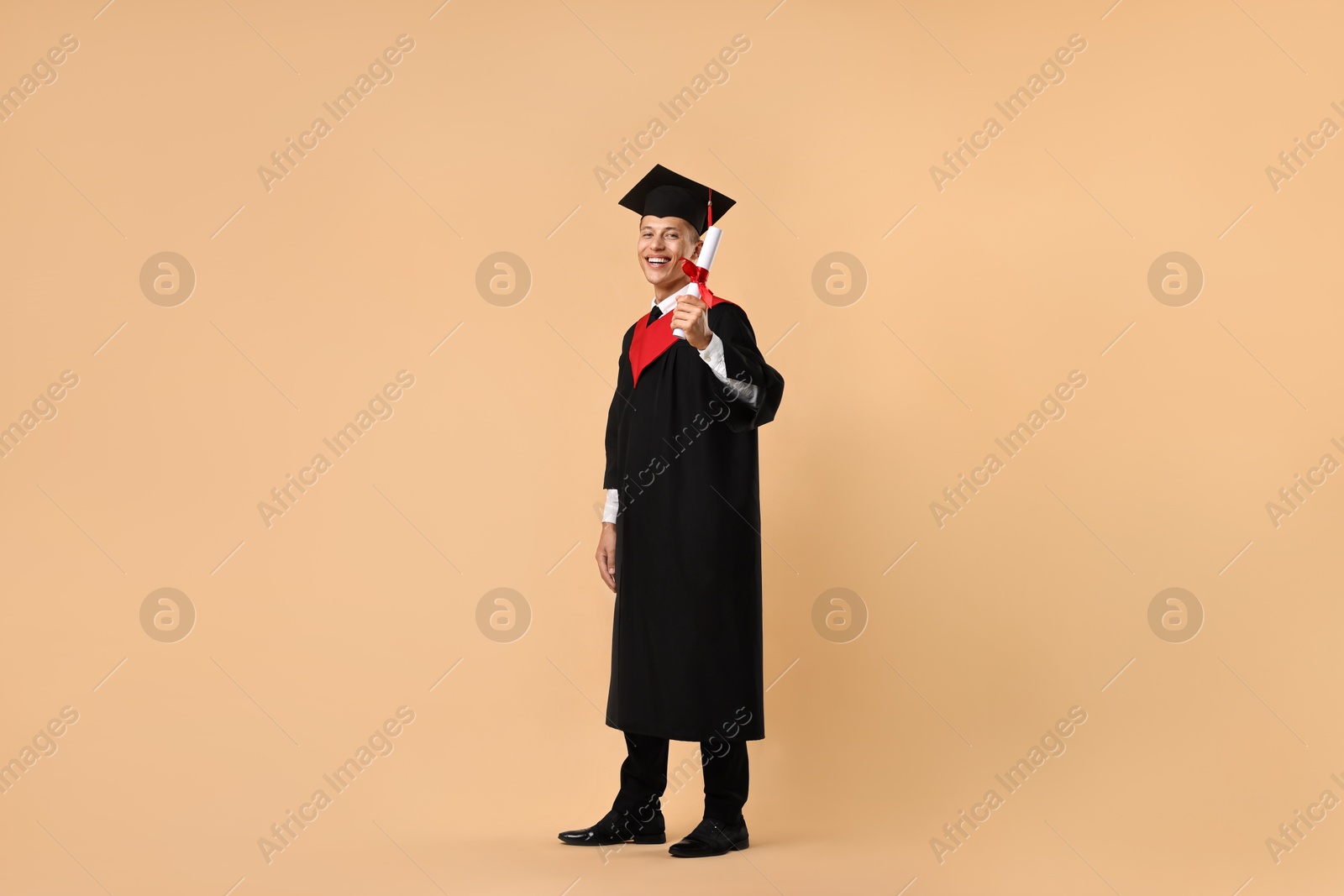 Photo of Happy student with diploma after graduation on beige background