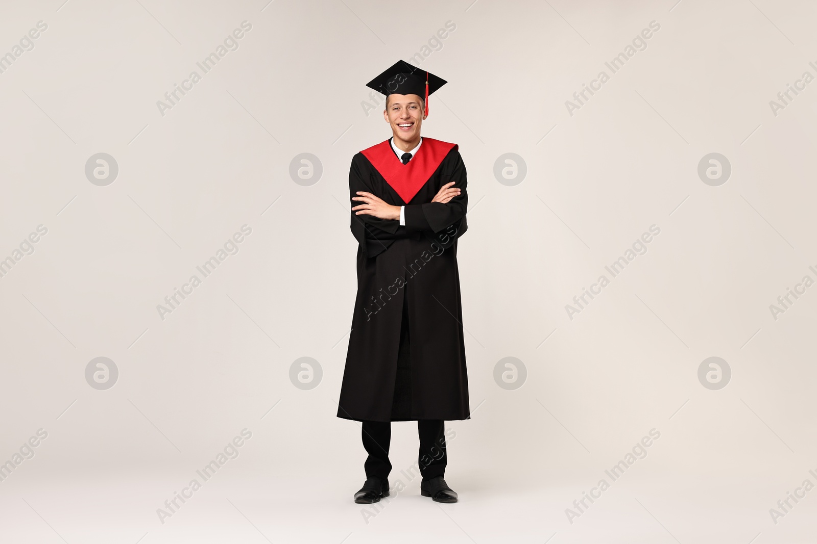 Photo of Happy student with crossed arms after graduation on light grey background