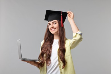 Photo of Happy student with laptop after graduation on grey background