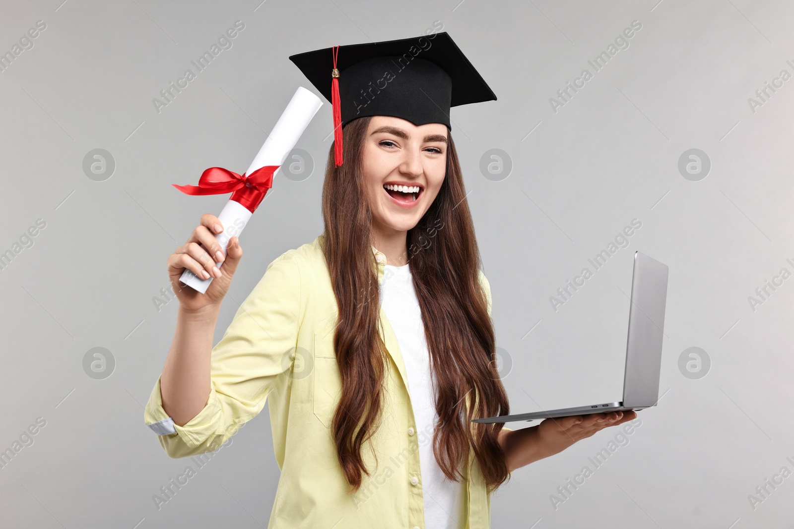 Photo of Happy student with laptop and diploma after graduation on grey background