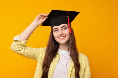 Photo of Happy student after graduation on orange background