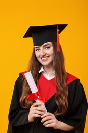 Photo of Happy student with diploma after graduation on orange background