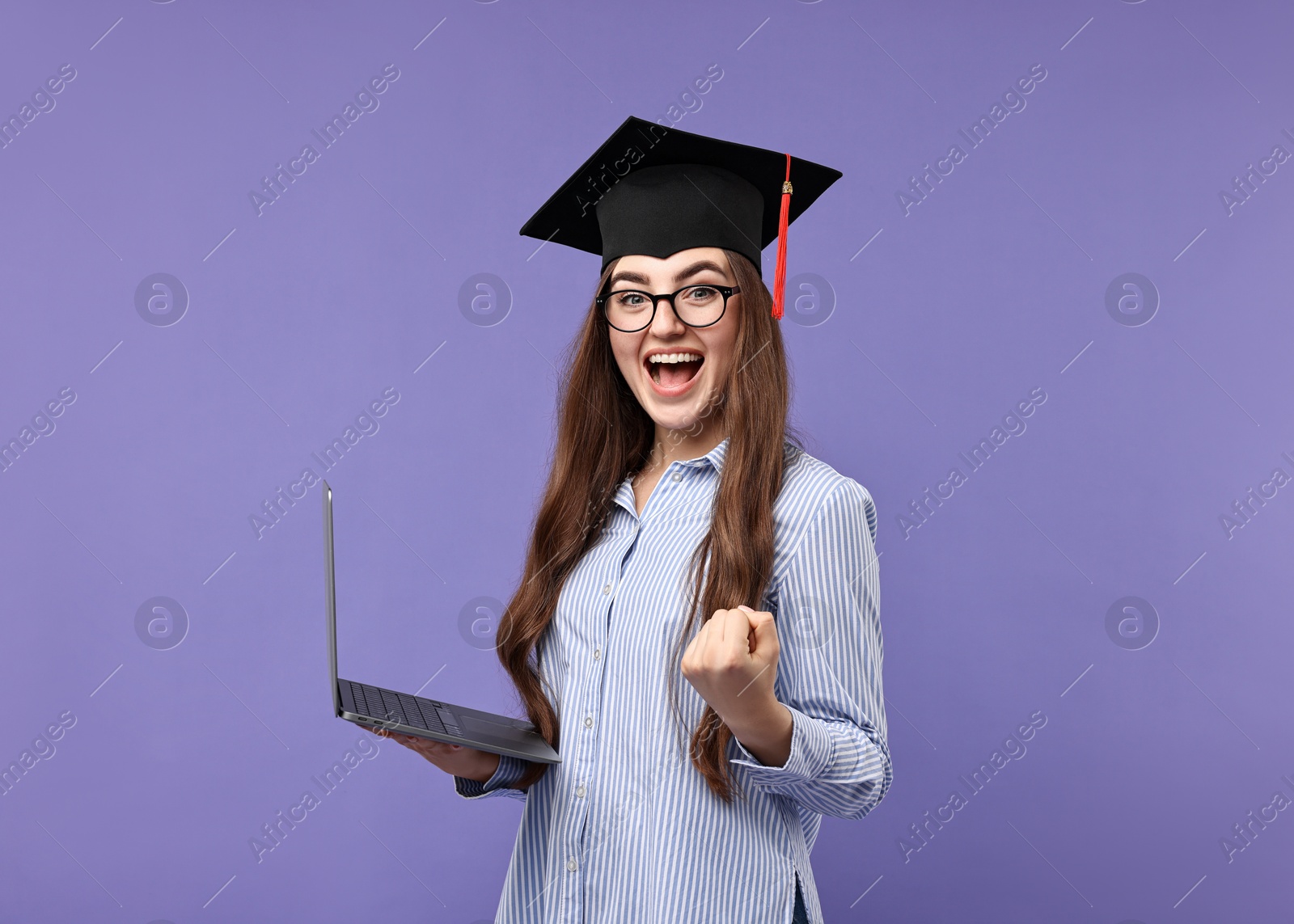 Photo of Happy student with laptop after graduation on violet background